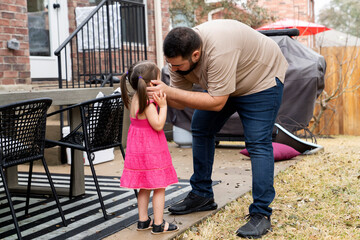 Dad talking to crying daughter in back yard of home