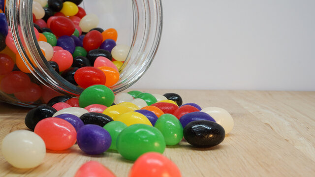 Colorful jelly beans spilling out of a glass jar. Copy space in top corner of image