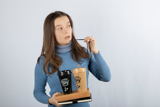 Image of a young girl model holding books and two cups of coffee