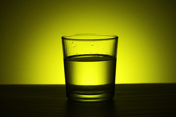 A glass with water at yellow background