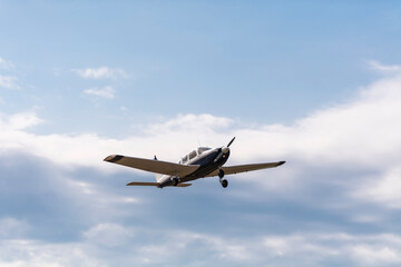Fototapeta na wymiar A light aircraft taking off into the cloudy blue sky
