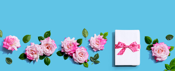 Fototapeta na wymiar Gift box with pink roses overhead view - flat lay