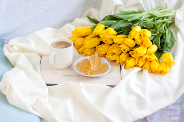 A bouquet of fresh yellow tulips and breakfast with coffee and homemade marmalade. Breakfast in bed. Spring flowers. The concept of spring and holiday, March 8, International Women's Day,