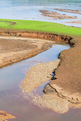 Path opened by the strength of a water stream in a dirt ground with stones. Hole opened on the ground by the water.