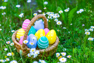 viele bunte Ostereier in einem Korb auf der Wiese	