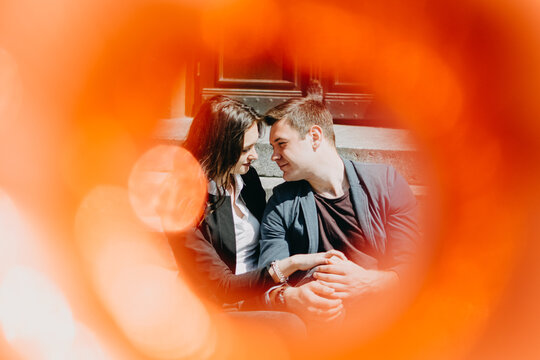 Spring love, dating, romance. Happy loving couple kissing and hugging on frame red blurred background. Selective focus
