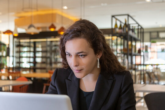 Beautiful young caucasian businesswoman in a restaurant in front of laptop