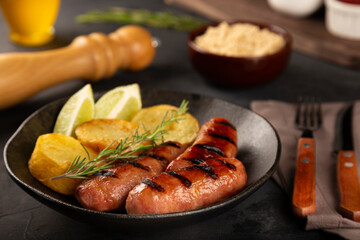 Grilled barbecue sausages on dark background.