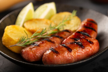 Grilled barbecue sausages on dark background.