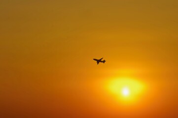 Defocused abstract background of orange sky with a silhouette aeroplane