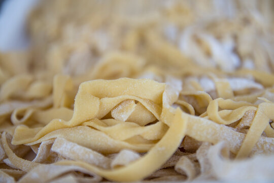 Macro picture of traditional Italian raw pasta Tagliatelle, selective focus image.  Nutrition concept. Italian kitchen. Food pasta background.