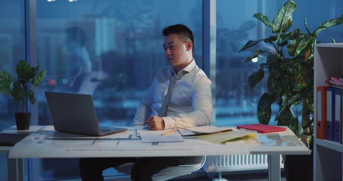 Asian angry businessman having problems at work hitting the table getting frustrated working long hours finishing project missing deadline. Emotions.