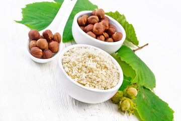 Flour and hazelnuts in bowls on board