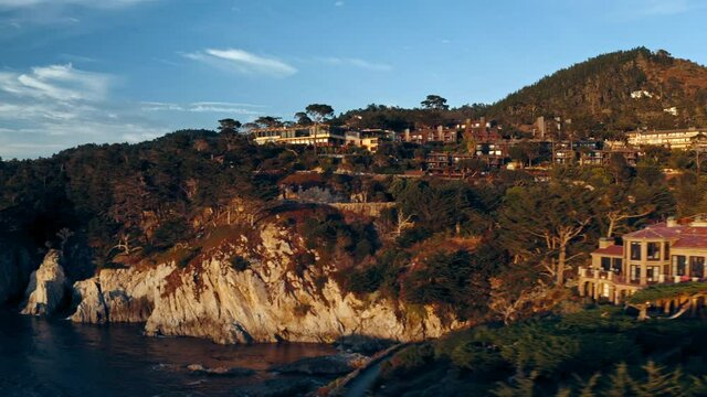 Aerial panning shot of houses on cliff over sea against sky at sunset, drone flying near rocky coastline - Rocky coastline at Carmel-by-th - Carmel-by-the-Sea, California