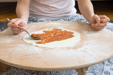 Homemade lahmacun preparation from start to finish. The filling is placed in the dough opened on the floor table.