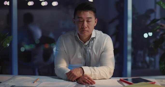 Young chinese businessman frustrating job problems having financial issues getting anxious inside corporate office at night. Business people problems.