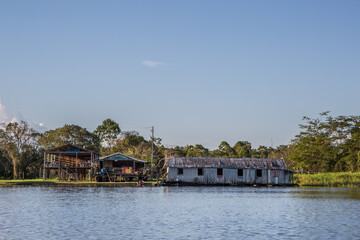 Fototapeta na wymiar A row of traditional wooden houses stood on stilts in an Amazonian riverside village in the Amazon River not far from Manaus, surrounded by rainforest and jungle trees in the State of Amazonas, Brazil