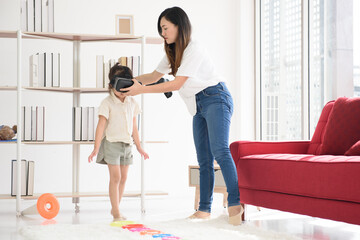 Asian mother and her little daughter play VR game for entertain , family joyful together in the house on holiday