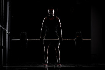 Athlete lifting barbell. Silhouette of a muscular man