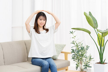 ソファーに座ってOKのジェスチャーをする若い女性