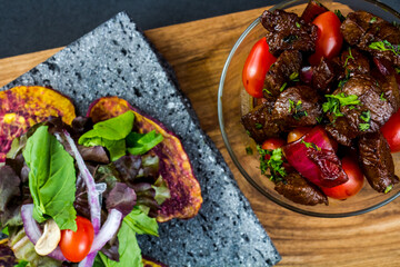 Sliced grilled beef barbecue steak and salad with tomatoes and arugula