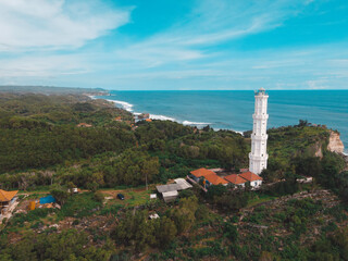 Fototapeta na wymiar Aerial view of Baron Beach in Gunung Kidul, Indonesia with lighthouse and traditional boat.