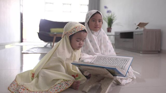 portrait of adorable muslim young kid read quran together at home. The Holy Quran verses (Quran 17: 1)