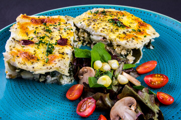Vegetarian lasagne topped with toasted pine nuts and melting cheeses. Salad