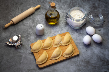 Fototapeta na wymiar Raw dumplings or pierogi (vareniki) with potato made at home. Traditional Russian dumplings on a wooden board.