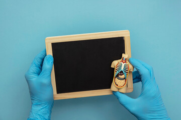 Doctor in blue surgical gloves holding a blank chalkboard