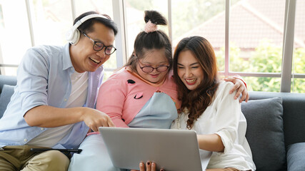 Downs Syndrome Sitting With Home Tutor Using Laptop For Lesson At Home. family using laptop at home