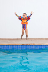Niña salta con flotadores del borde de la piscina