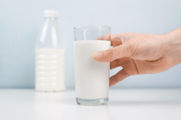Male hand taking glass of milk in the kitchen at home. Close-up, selective focus