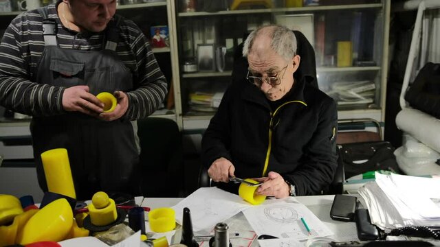 An engineer at a work table measures a part with a caliper. Director Measures the polyurethane product with a ruler and checks the work of the turner