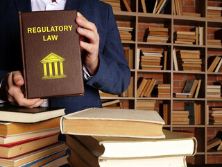 Lawyer holds REGULATORY LAW book. Regulatory law refers to law promulgated by an executive...