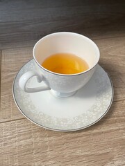 yellow tea in a white cup on a saucer. aristocrats