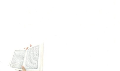 Blurred Photo of man reading the Koran ready for Ramadan.  Arabic on the cover is translated as the...