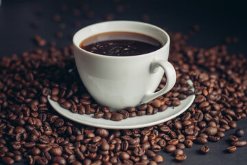 coffee beans sprinkled on a gray table and a cup saucer arabica drink