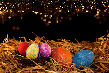 Fototapeta na wymiar beautiful colorful Easter eggs lie on the straw with a shiny background