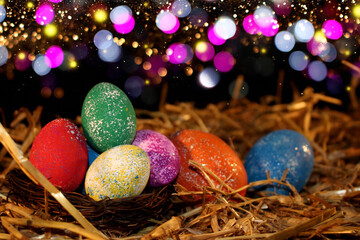 beautiful colorful Easter eggs lie on the straw with a shiny background