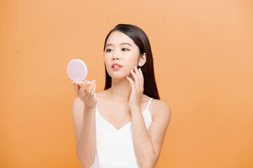 Beauty portrait of a happy attractive woman examining her face while looking at the mirror isolated...