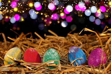 beautiful colorful Easter eggs lie on the straw with a shiny background
