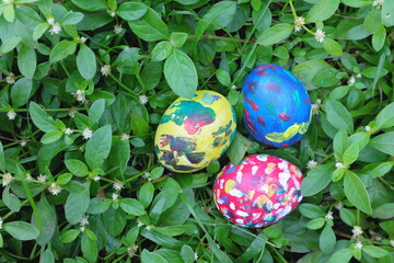 Easter sunday concept. Three colorful eggs hidden on grass garden with copy space.