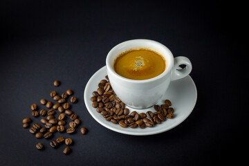White cup of black coffee with coffee beans around. Black background.