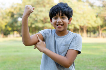 Indian boy showing muscles of the arm in the park. Concept of health
