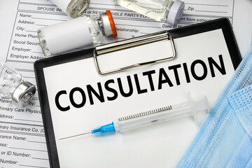 The word consultation is written on a stationery tablet that lies on the patient's medical questionnaire near the ampoules and a syringe with a medical mask.