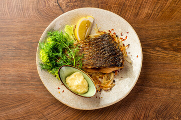 Piece of fried carp with sauce and lemon on a plate 
