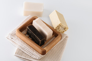 natural handmade soap on a wooden soap dish, side view, on a bath towel, light background