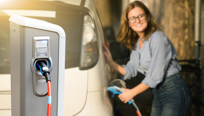 Close up of charging station on a background of a woman near an electric car