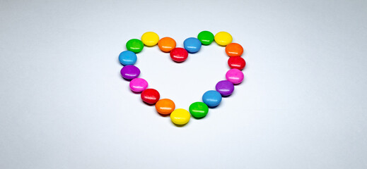 Selective focus of colorful button chocolates arranged in the shape of a heart.